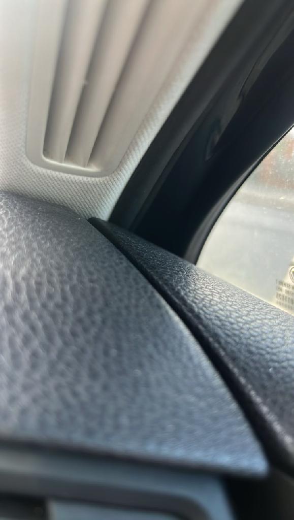 Close-up of a dark carpet edge and adjoining upholstery with visible dullness and general embedded soiling in the fibres.